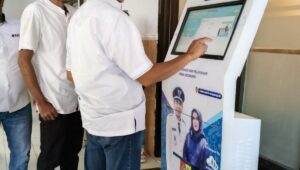Djoko Susanto Wabup Jember mencoba mesin anjungan pelayanan mandiri semabari mengisi Buku Tamu di Dampingi Kades Sidomukti Sunardi Hadi (Foto Istimewah : Surya )